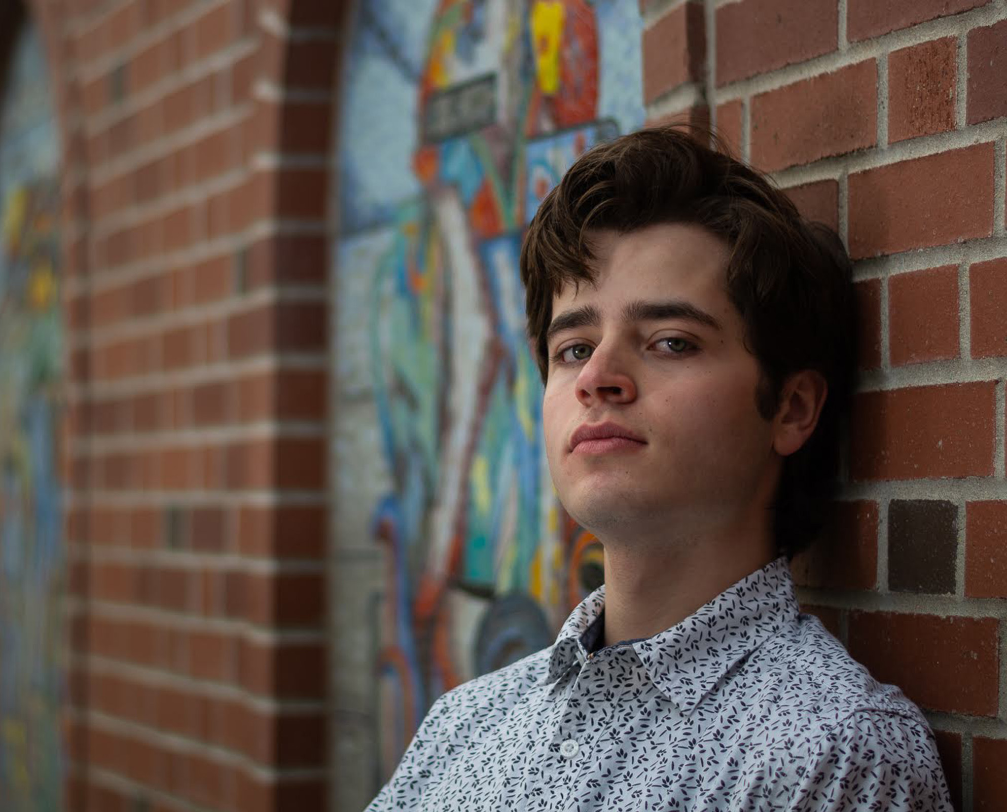 Student standing by brick wall