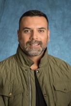 man in green jacket against blue backdrop
