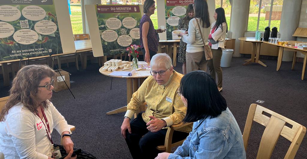 Three women chatting at table at MERISTEM celebration